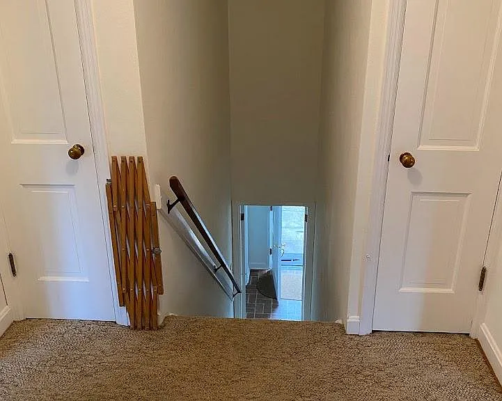 Upstairs landing with carpeting and carpeting down the steps with an attic fan overhead