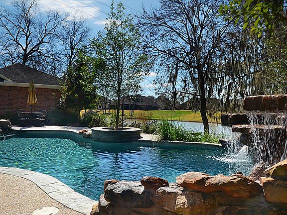 The pool sits up high and provides an elevated view of natural Oxbow Lake as an ideal backdrop.  Notice the tiered waterfall in Spa and also how the Garage provides both shelter and privacy.