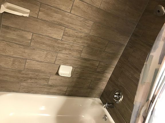 New porcelain steel tub, tile enclosure, shower faucet