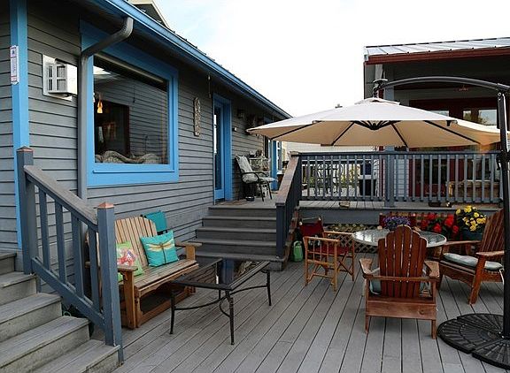 Another deck with stairs from front deck and living room, artist studio behind umbrella.