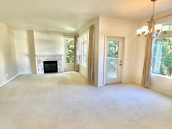 Large, light-filled living room lined with windows and a gas fireplace