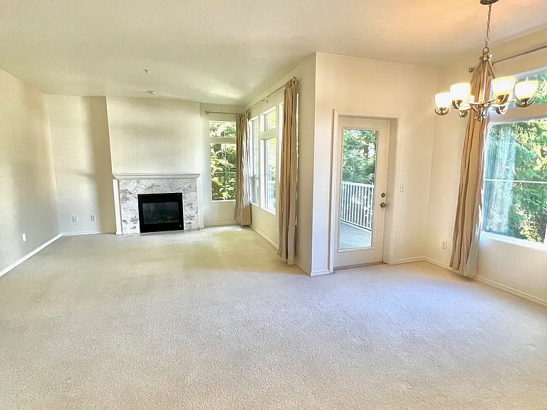 Large, light-filled living room lined with windows and a gas fireplace
