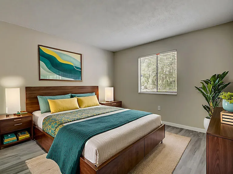 Inviting bedroom with modern decor featuring a wooden bed, colorful bedding, and large window providing natural light.