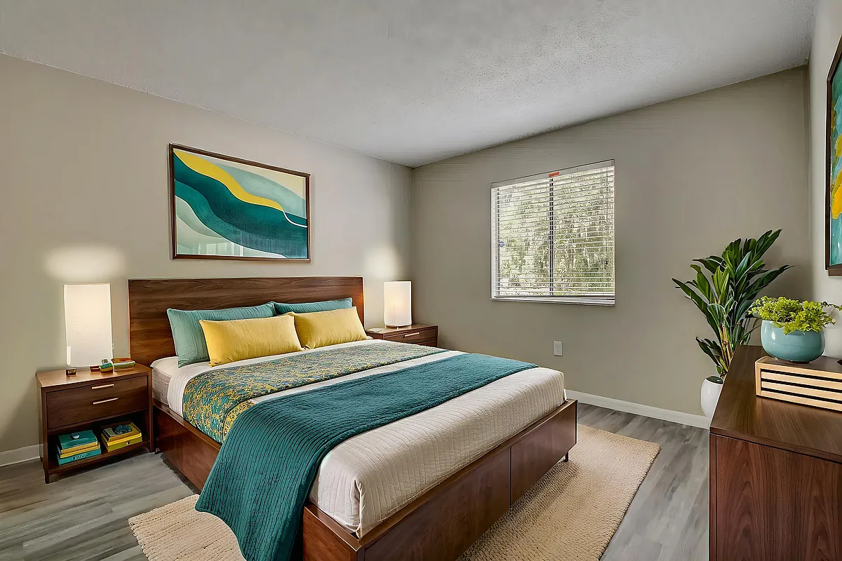 Inviting bedroom with modern decor featuring a wooden bed, colorful bedding, and large window providing natural light. - Derby Park Apartments