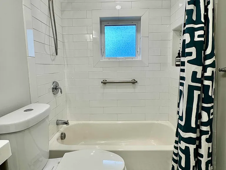 Updated second full bathroom with tub, shower, subway tile, and natural light.