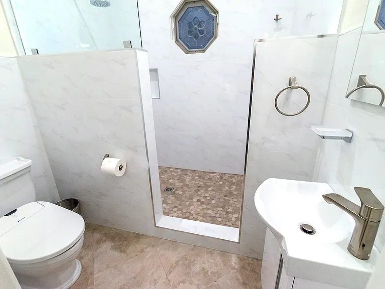 Large ensuite bathroom with step-in shower, vanity and small sink, with toilet that has an electric bidet seat.