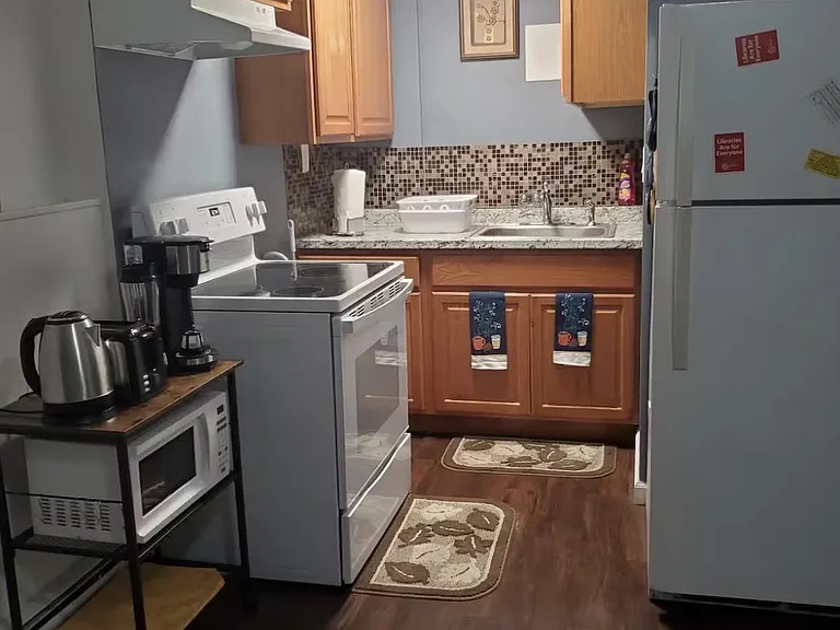 Efficient galley kitchen with ample wood cabinetry, mosaic backsplash, and full appliance set for everyday cooking.