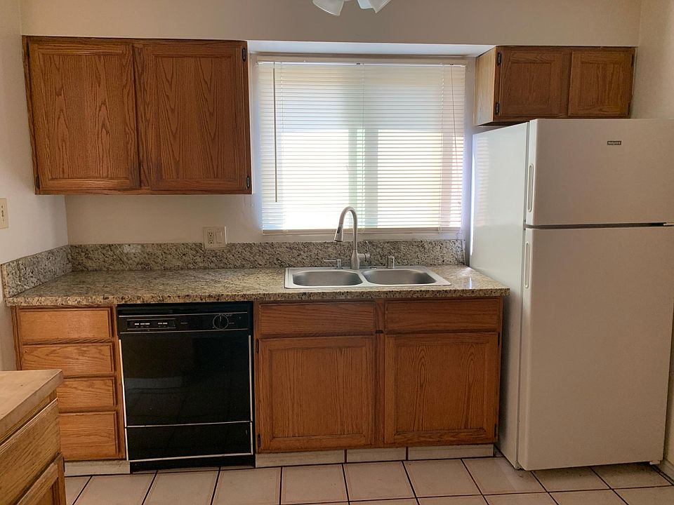Kitchen cabinets with granite countertops, refrigerator, garbage disposal, & dishwasher.