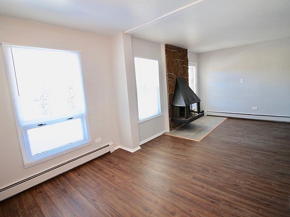 View of main living area, entry door, and fireplace from dining room.