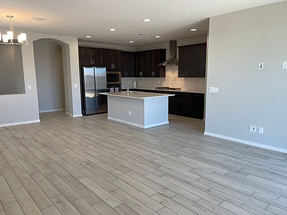 Large open concept kitchen, living room and dining room with neutral tile plank, grouted floors.