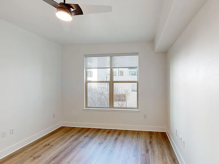 Spacious apartment bedroom with wood-style flooring.