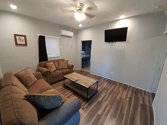 Living room frontal view with Ac/Heat mini split. Laminate flooring, 42 inch TV mounted. Living room assesories include a 42 inch ceiling fan with sofa and loveseat. Very relaxing and extremely comfortable.