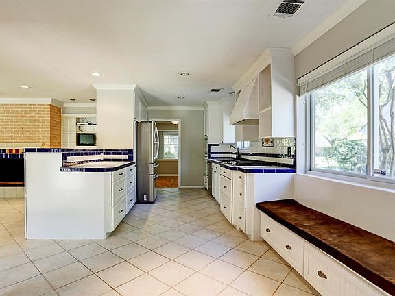 Large kitchen has freshly painted cabinets and tile counters. There is a window bench where you could place your breakfast table. Not shown is the utility room with built-in desk.