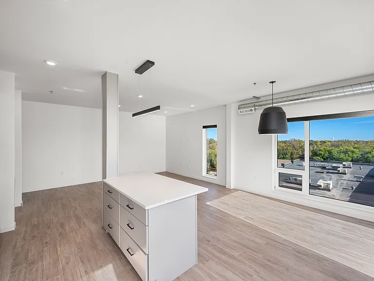 Bright and modern open-concept apartment with sleek kitchen island, large windows, and scenic views. Bright and modern open-concept apartment with sleek kitchen island, large windows, and scenic views.