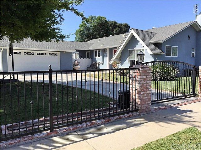 Front yard with circular driveway, wrought iron fencing and automatic gates