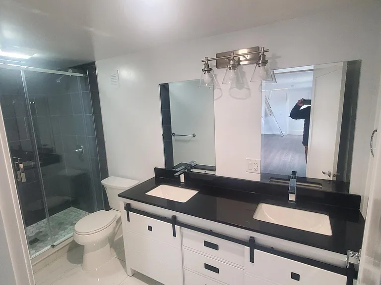 Bathroom is double sink, quartz counter to match, marble floor, walk-in shower with stone surround