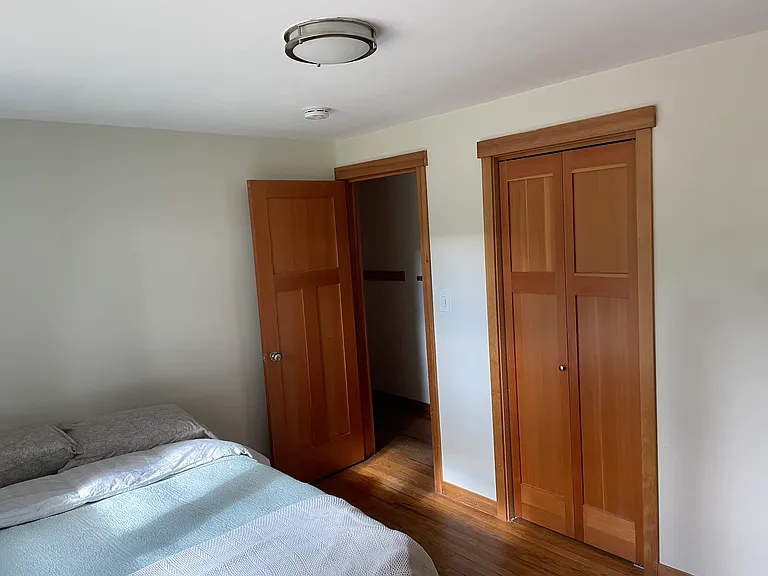 Medium sized bedroom with closet, oak floors, and two windows