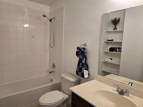 Full bathroom featuring toilet, vanity, and tiled shower / bath