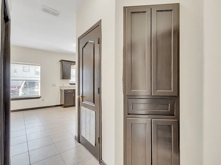 Hallway of Merida Vista Apartments in Laredo, Texas, with a door and storage cabinets lining the walls