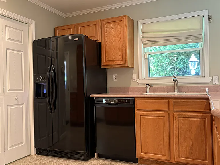 Well-designed kitchen with extensive cabinet storage, pantry cabinetry, gas range, built-in microwave, and convenient access to the laundry room and covered carport.