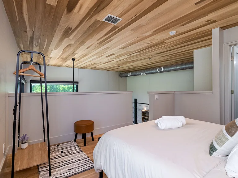 Bedroom 2 is lofted with a queen bed with open closet in the corner.