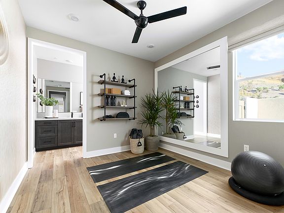 A modern and minimalist entryway with a black ceiling fan, wooden floors, and a black and white patt