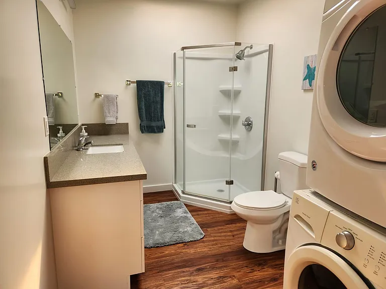 Bathroom with stacked washer and dryer, large vanity, shower stall.