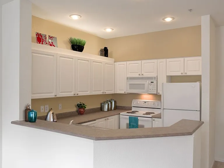 Classic Package I kitchen with white appliances, laminate countertops, white cabinetry, and laminate or hard surface flooring