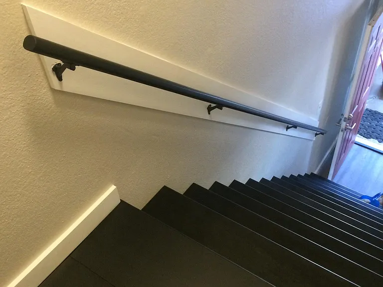Staircase with handrail leading to lower level. Notice placement of open front door.