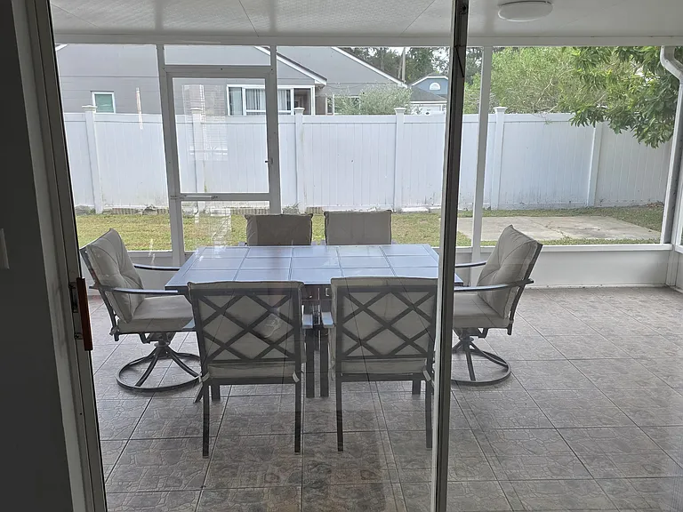 Entrance to the screened-in outdoor patio area. Patio table and seating are included with the home so tenants can immediately enjoy and relax in the outdoor space without needing to furnish it themselves
