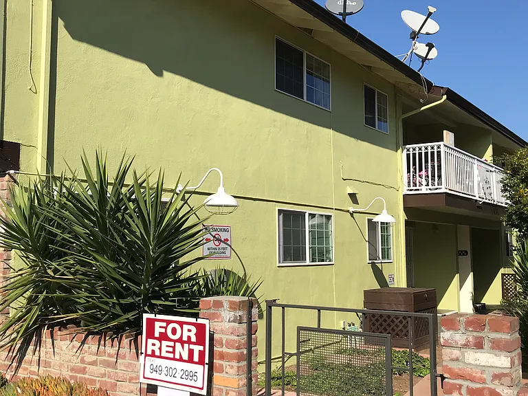 Cozy 600 square foot apartment with a front porch entry that opens to a landscaped common area and concrete walkway with wooden benches.