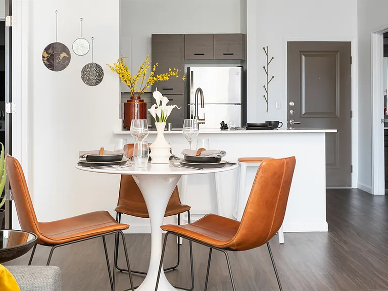 Apartment kitchen with stainless steel appliances and dining room with wood-style flooring.