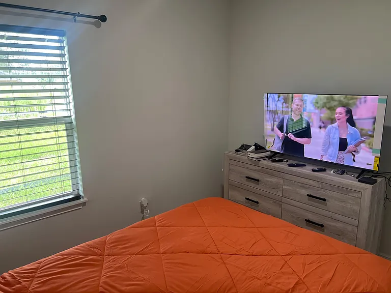 Private bedroom with a large window and blinds, plus a dresser topped with a TV for convenient in-room storage and entertainm