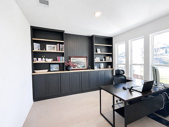 Dedicated home office featuring newly installed custom built-ins, abundant natural light, and a pleasant view facing the front of the home. Ideal for remote work or a quiet study space.