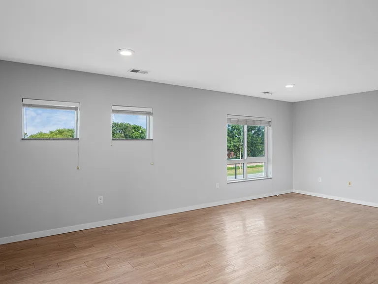 Bright and spacious room with large windows, elegant hardwood flooring, and neutral walls creating an inviting atmosphere. Bright and spacious room with large windows, elegant hardwood flooring, and neutral walls creating an inviting atmosphere.