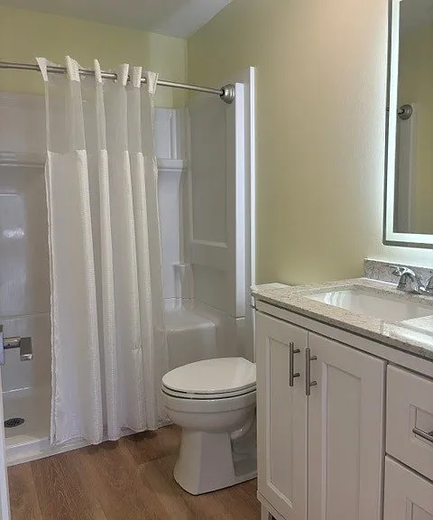 Bathroom has large shower, vanity for storage and backlit mirror.
