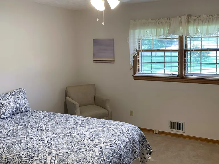 Dual windows for natural light, seating, nightstand, lamp, and reach in closet!