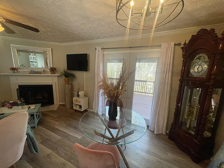 Open living area with a fireplace, wall-mounted TV, and sliding doors to a deck for easy indoor-outdoor living.