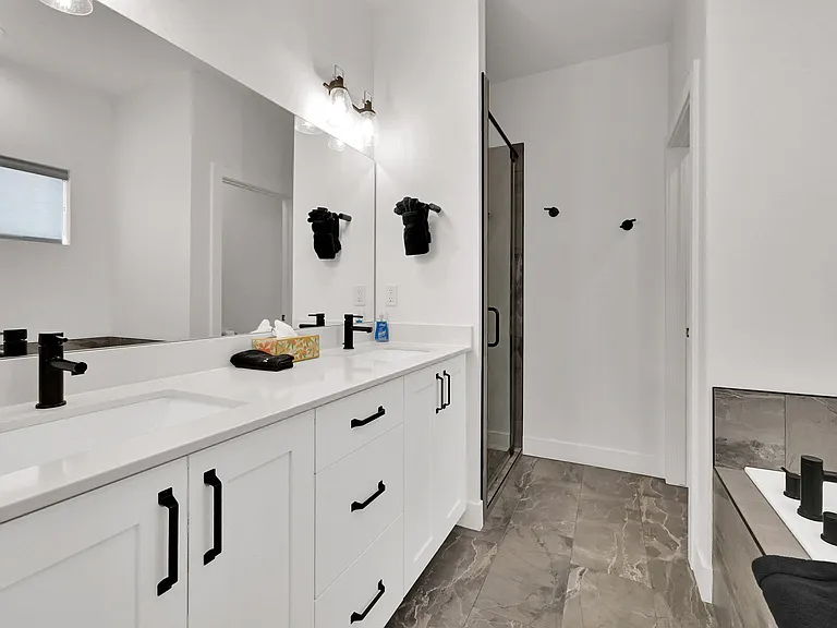 Master bathroom with his and hers sinks, walk in shower, large bathtub, and separate toilet room