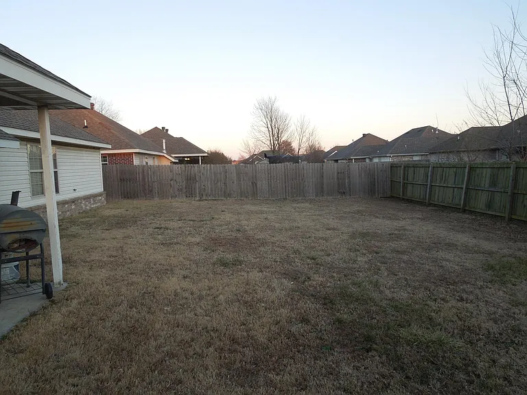 fenced back yard and corner of covered patio