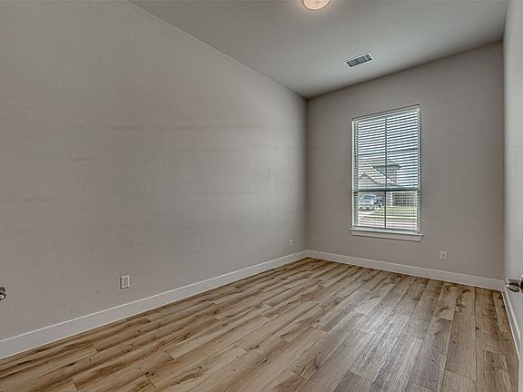Room featuring wood-finish flooring, neutral wall tones, and white trim