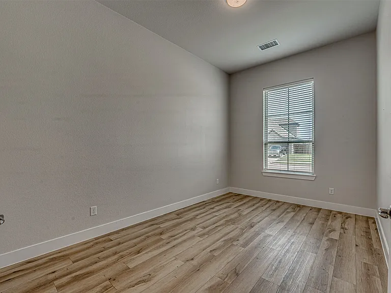 Room featuring wood-finish flooring, neutral wall tones, and white trim