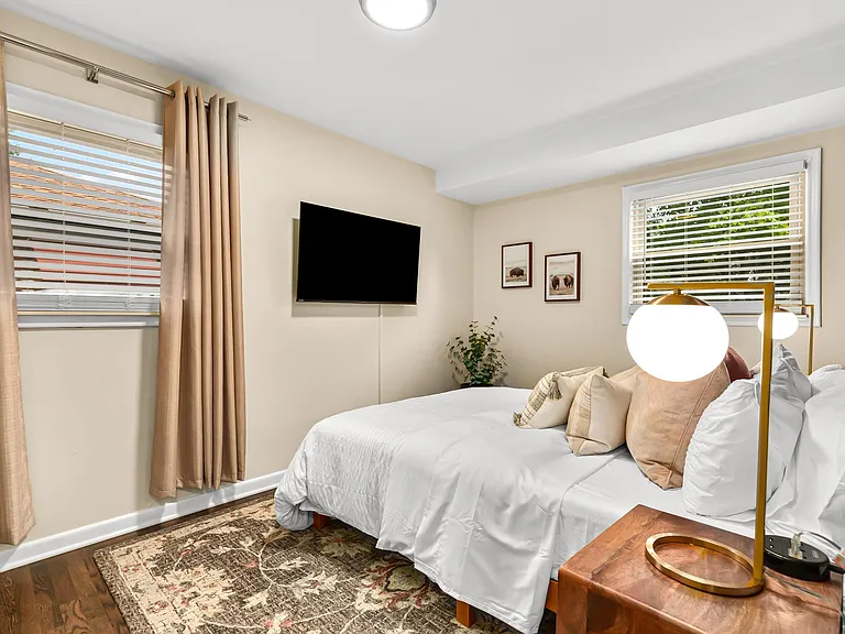 A bedroom with a large window lets in plenty of natural light, making it feel bright and airy.