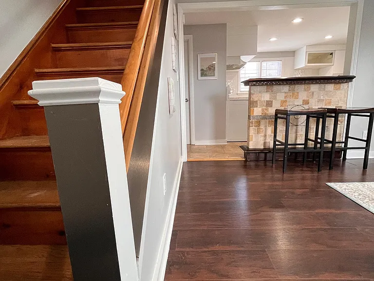 Open main level features hardwood floors, staircase entry, and a breakfast bar that connects to the kitchen.