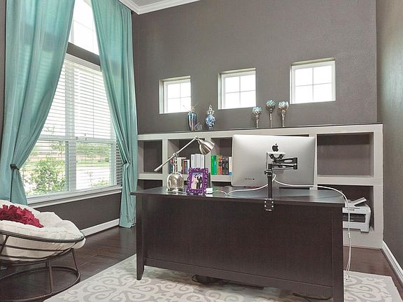 This formal living area currently used as a study features 2" blinds, wood flooring, custom built ins, crown moulding and decorative paint.