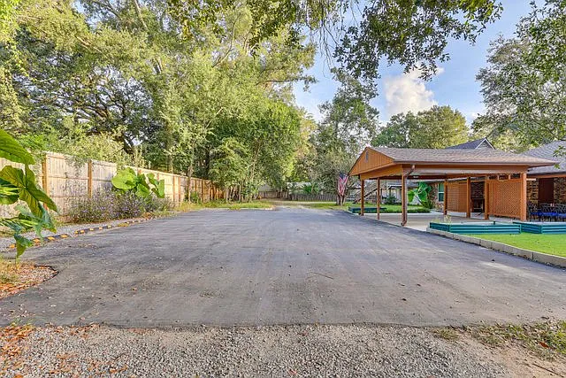 Fully paved parking area behind home with marked spaces, in addition to 1-car carport - covered to house