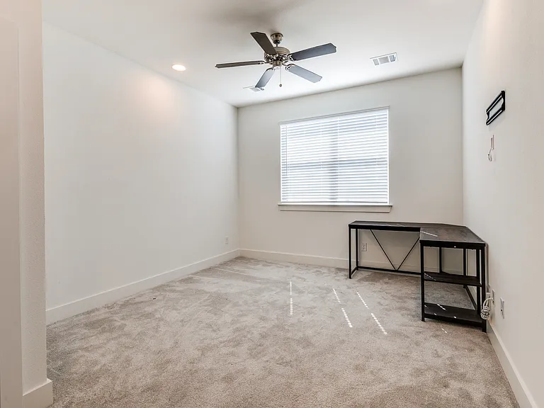 Master bedroom with ceiling fan and lots of natural sunlight (desk has been removed.)