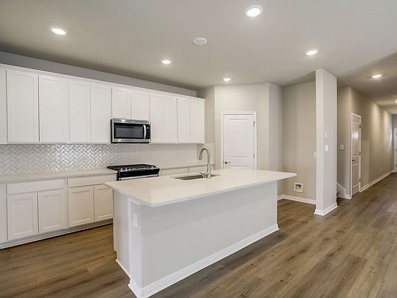 This beautiful kitchen features linen-colored cabinets and quartz countertops.