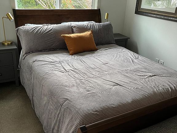 South bedroom with light blocking shade, air conditioning, bench at foot of bed, and full closet.