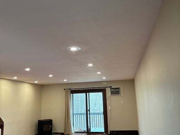 large freshly painted dining/living area with sliders to deck and pellet stove